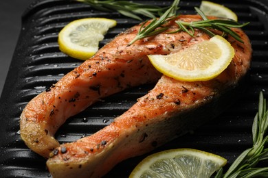 Photo of Cooking salmon. Grill with tasty fish steak, lemon and rosemary, closeup