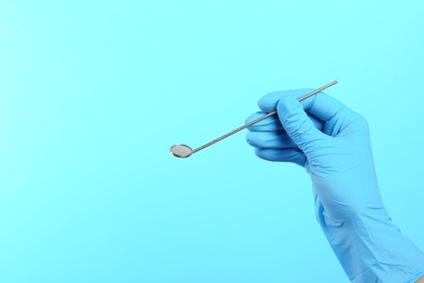 Photo of Dentist holding mouth mirror on color background. Mouth and teeth care