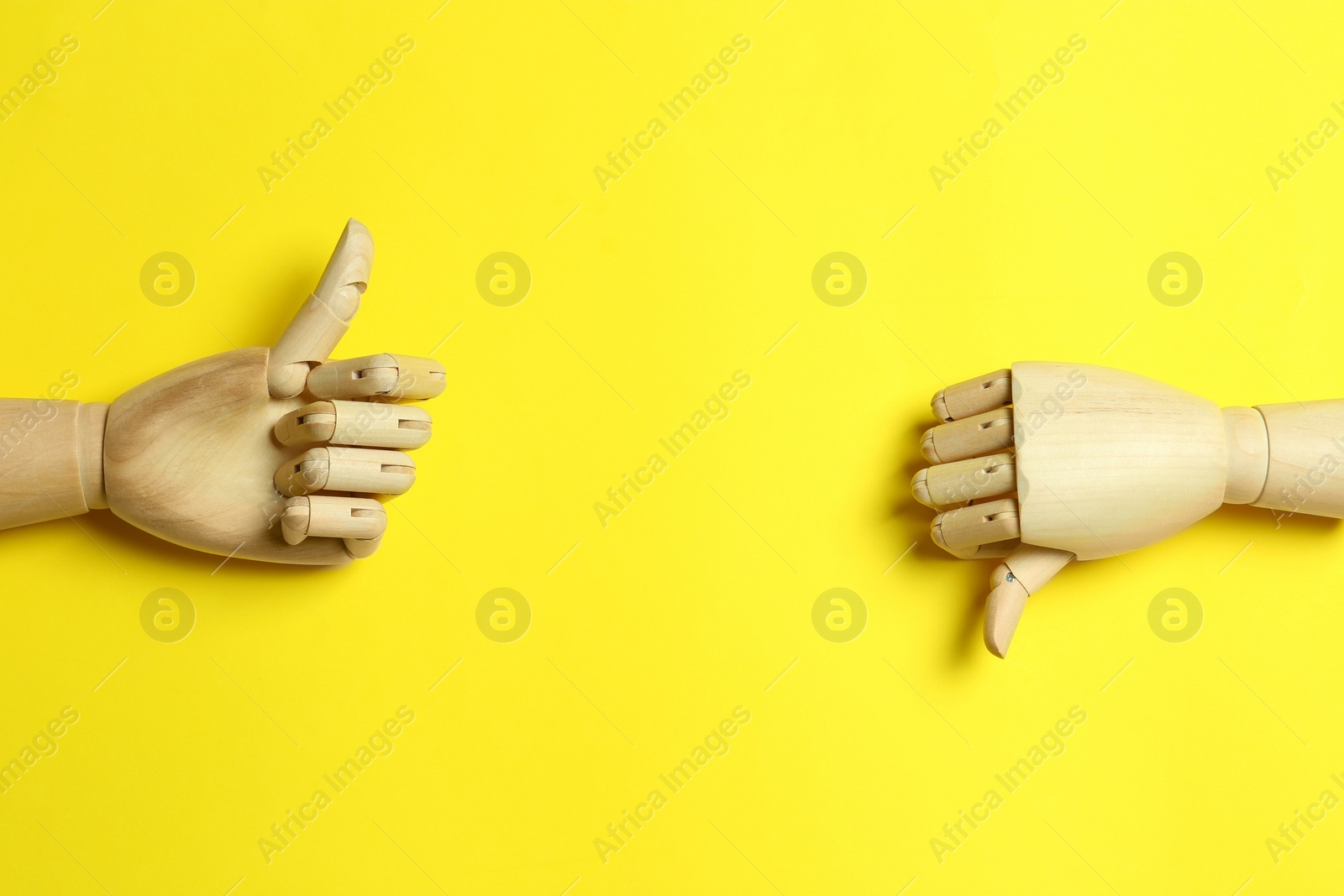 Photo of Wooden mannequin hands on yellow background, flat lay