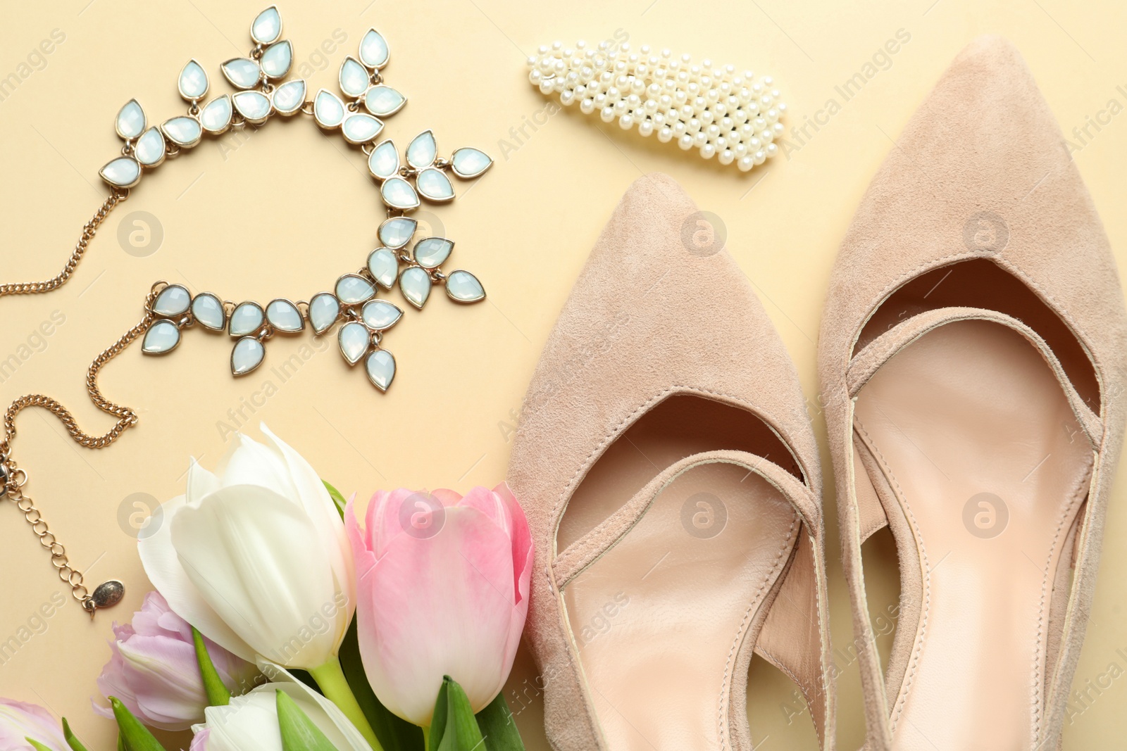 Photo of Stylish shoes, beautiful flowers and accessories on beige background, flat lay