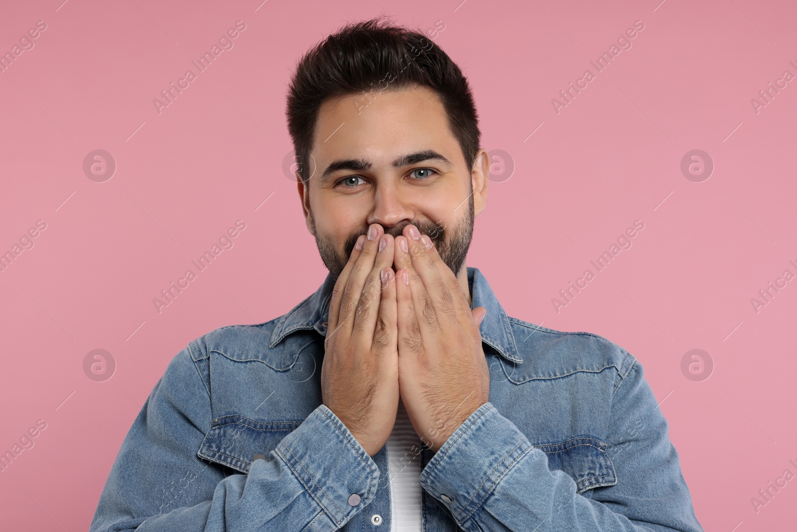 Photo of Embarrassed man covering mouth with hands on pink background