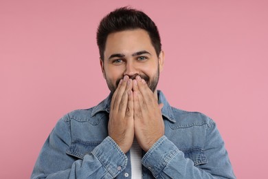 Photo of Embarrassed man covering mouth with hands on pink background