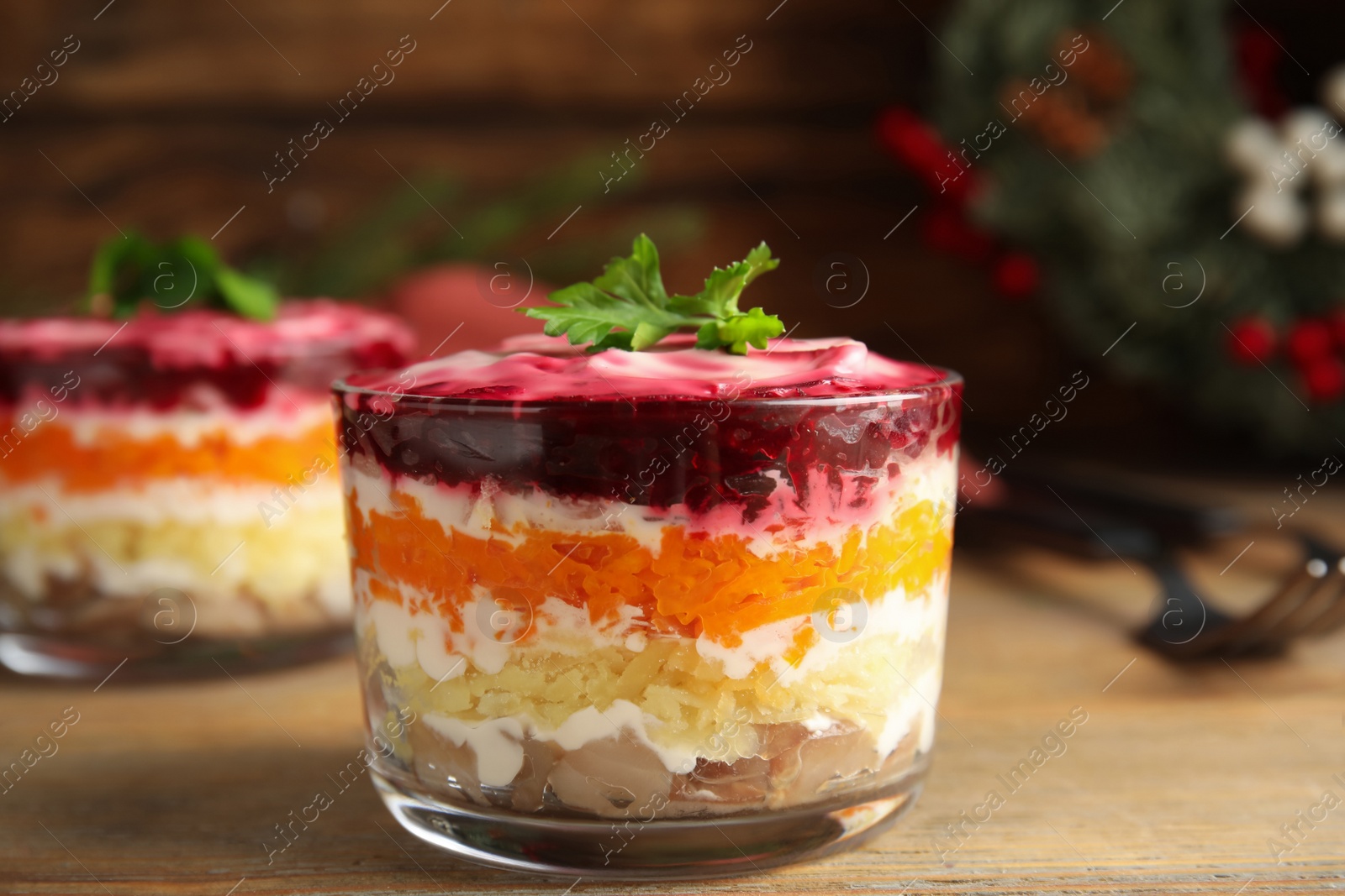 Photo of Herring under fur coat served on wooden table, closeup. Traditional russian salad