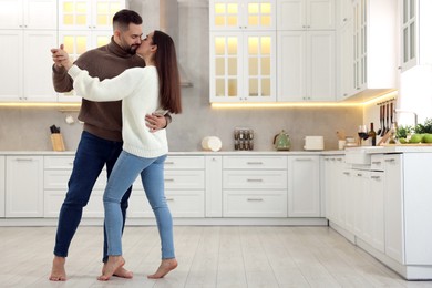 Affectionate young couple dancing and kissing in kitchen. Space for text