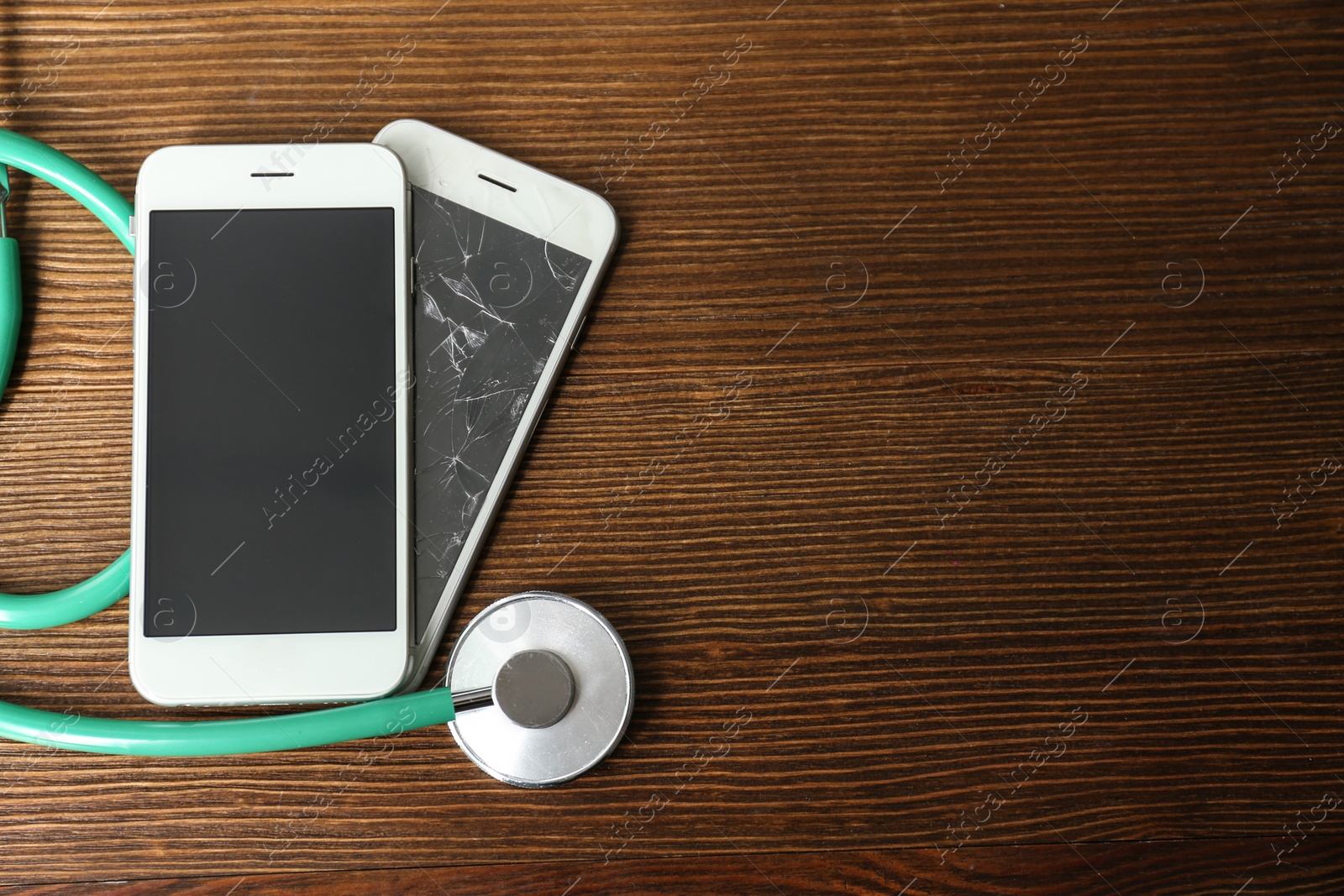 Photo of Smartphones and stethoscope on wooden table, flat lay with space for text. Repairing service