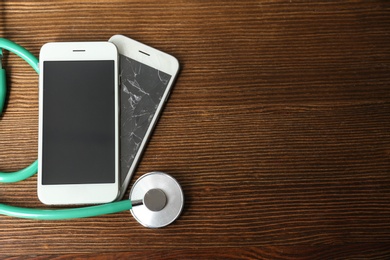 Photo of Smartphones and stethoscope on wooden table, flat lay with space for text. Repairing service