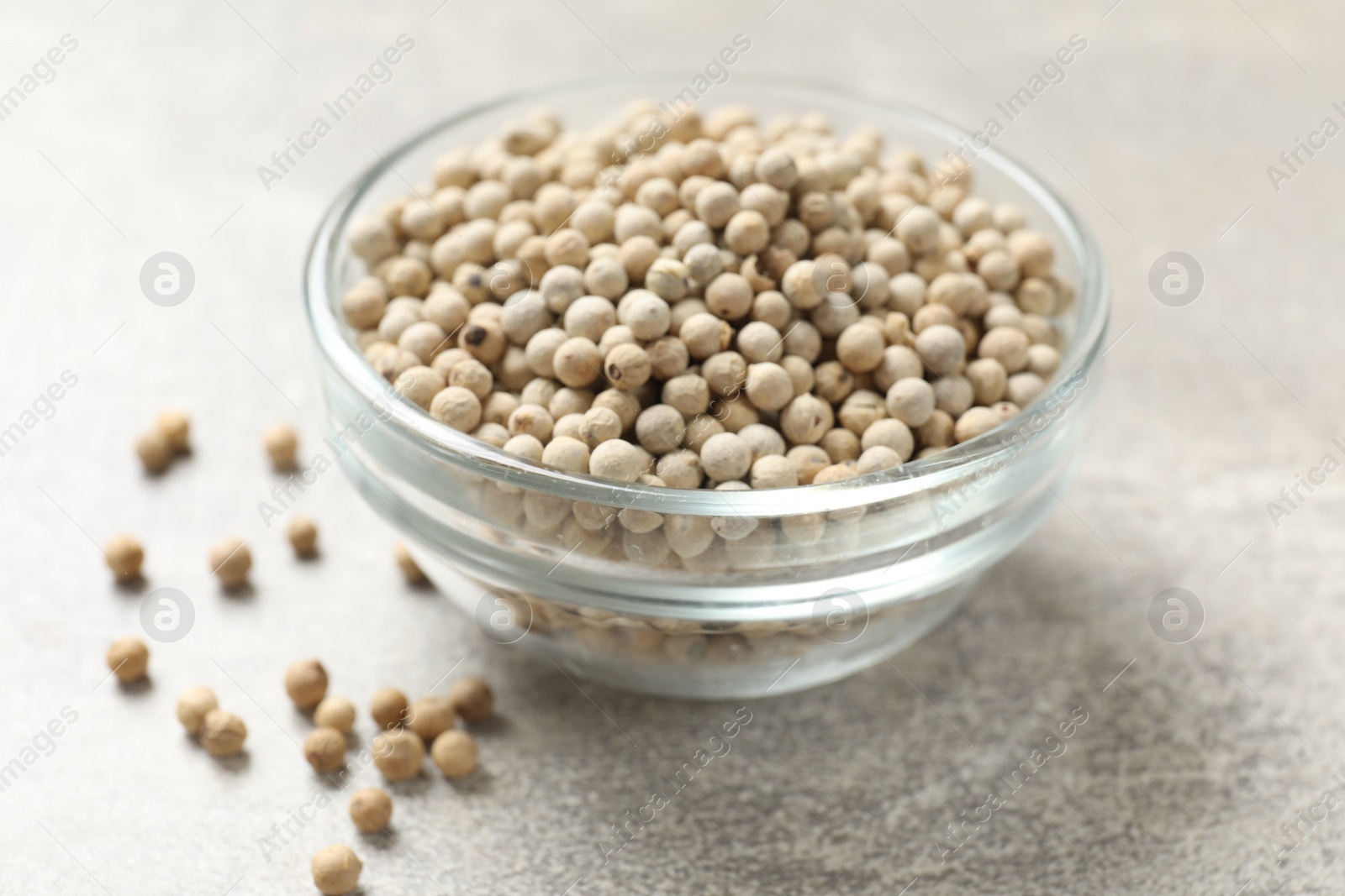 Photo of Aromatic spice. White pepper in bowl on light grey table, closeup