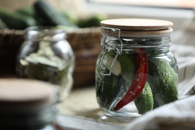 Photo of Jar of pickled cucumbers on wooden table, closeup. Space for text