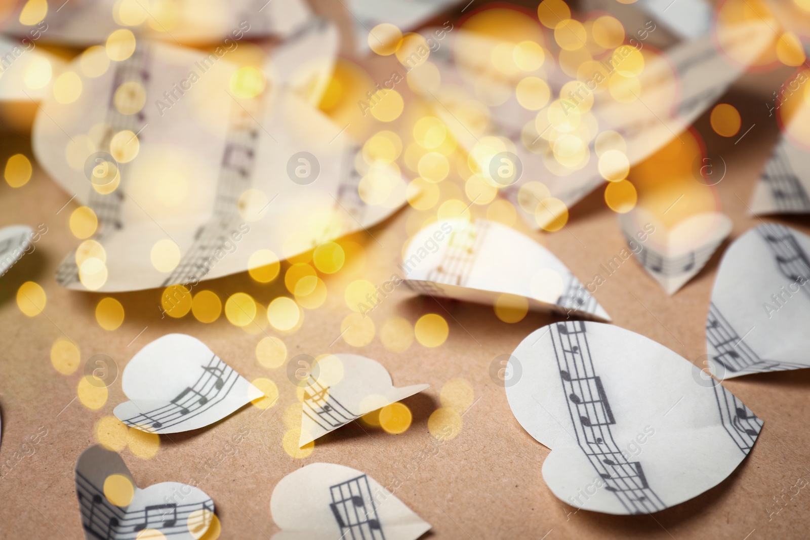 Image of Christmas and New Year music. Hearts cut out from music sheets on wooden background, bokeh effect