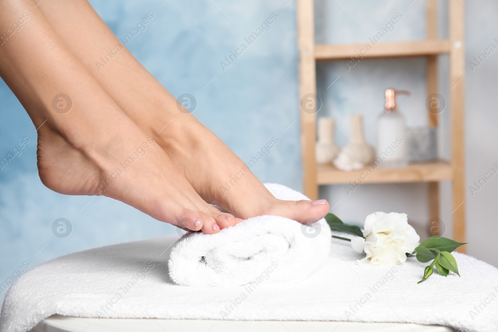 Photo of Woman with smooth feet on white towel indoors, closeup. Spa treatment