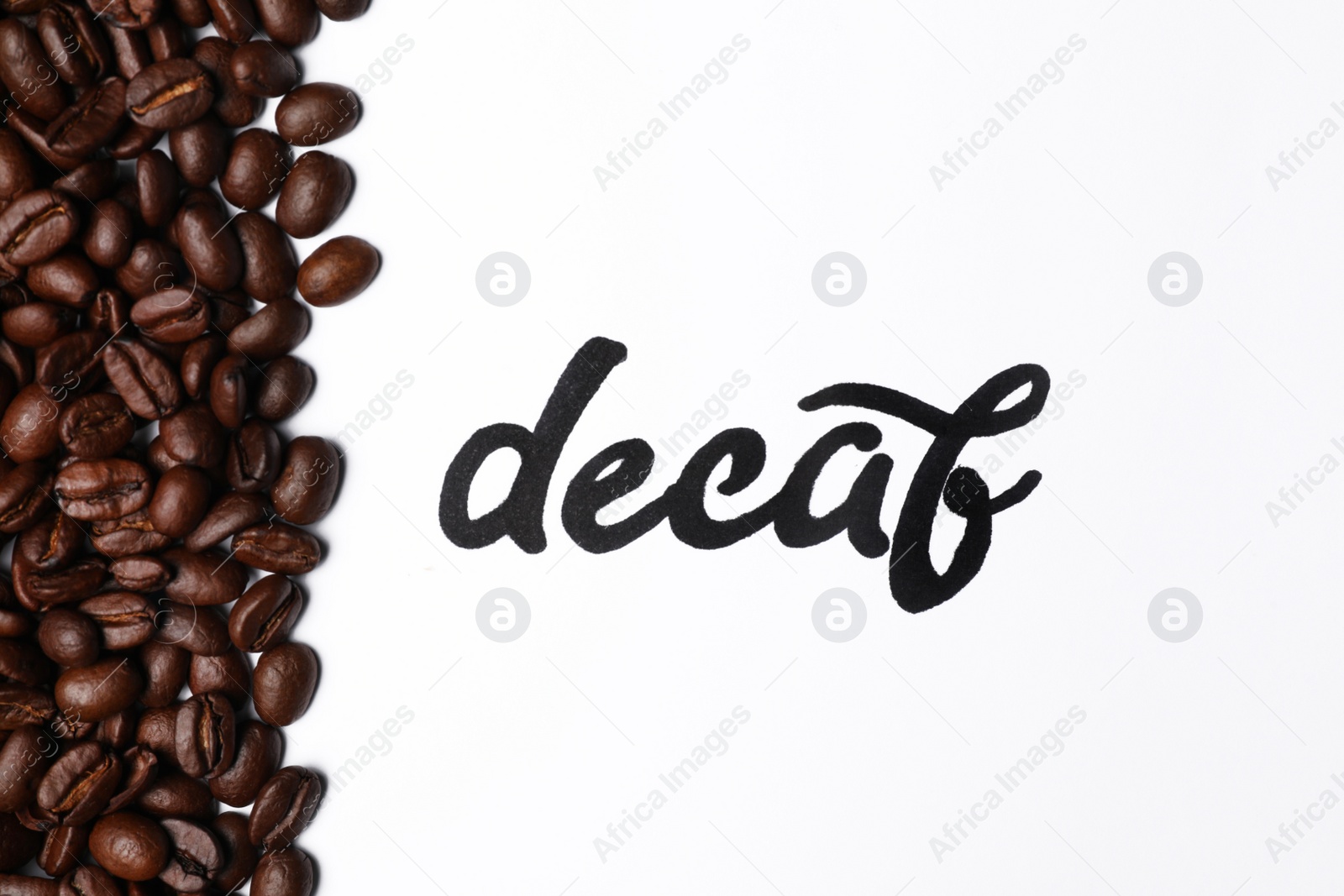 Photo of Word Decaf and coffee beans on white background, top view