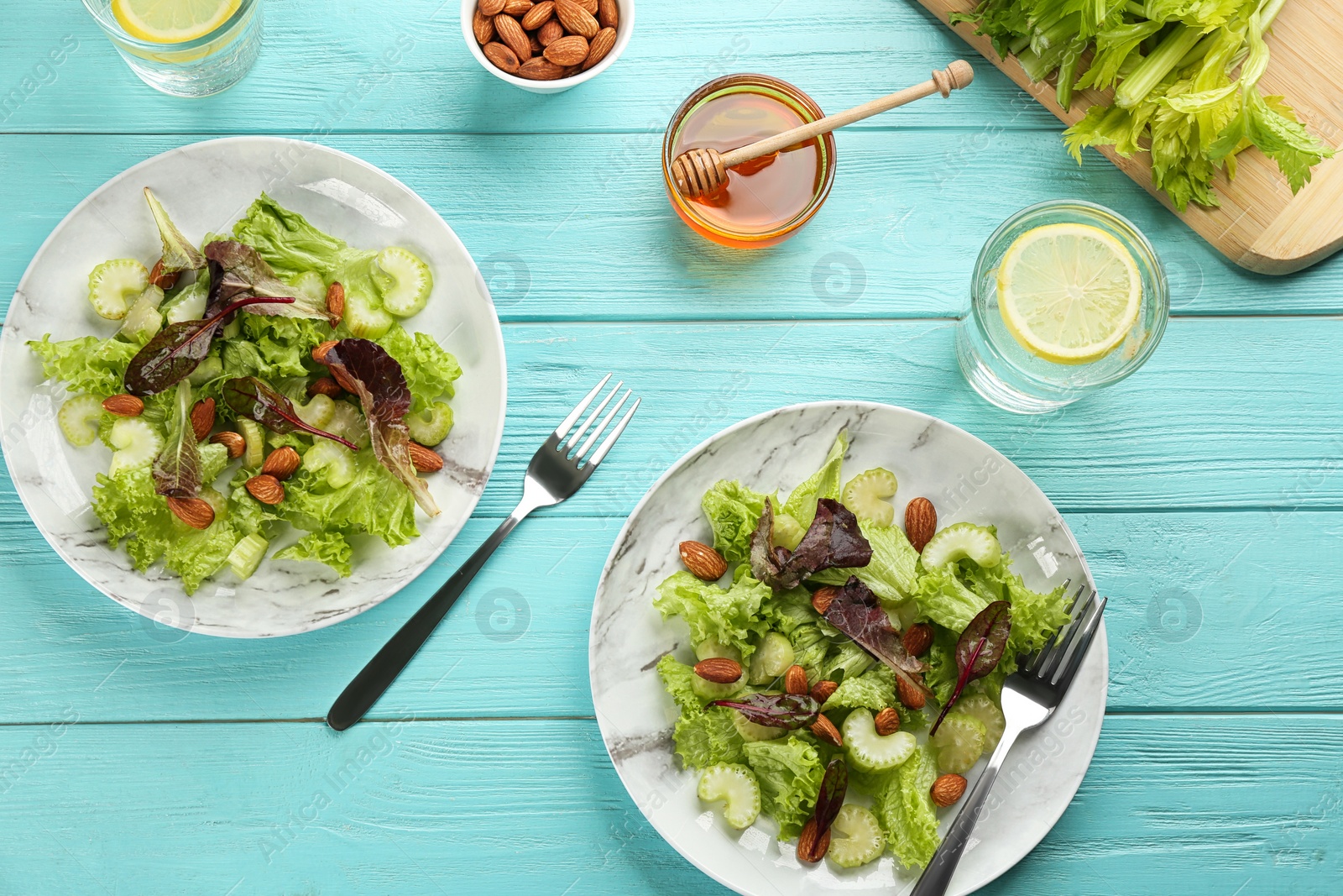 Photo of Delicious fresh celery salads served on light blue wooden table, flat lay