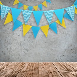 Image of Empty wooden table and decorative bunting flags hanging on grey wall