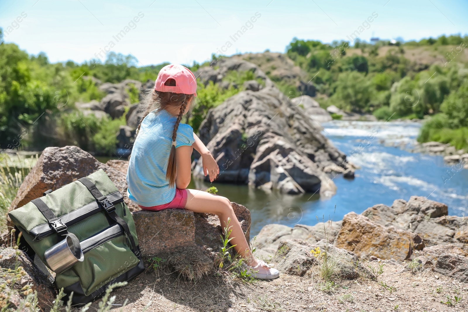 Photo of Little girl on rock near river. Summer camp