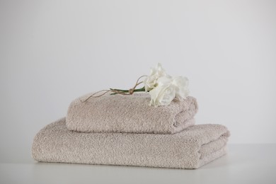 Soft folded towels with eustoma flowers on white table