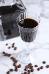 Photo of Coffee liqueur and beans on white table, closeup