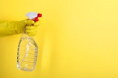 Photo of Woman spraying product from bottle on yellow background, closeup. Space for text