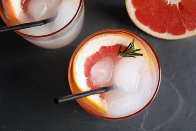 Glasses of cocktail and grapefruit slice on dark table, flat lay