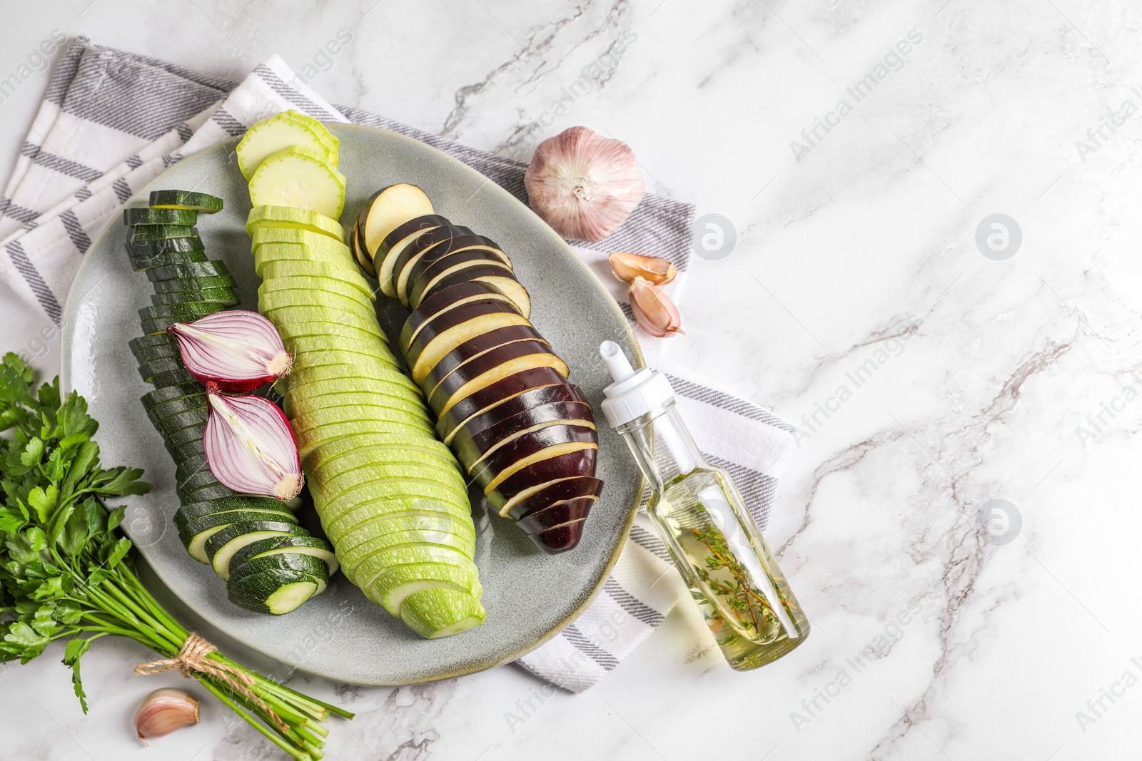 Photo of Cooking delicious ratatouille. Fresh ripe vegetables and plate on white marble table, flat lay. Space for text