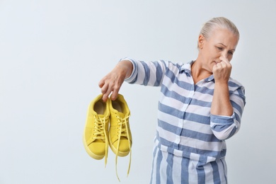 Photo of Woman feeling bad smell from shoes on white background. Air freshener