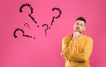 Image of Emotional man with drawings of question marks on pink background