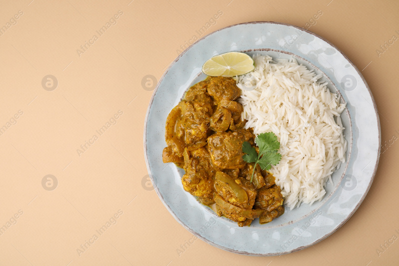 Photo of Delicious chicken curry with rice on beige background, top view. Space for text