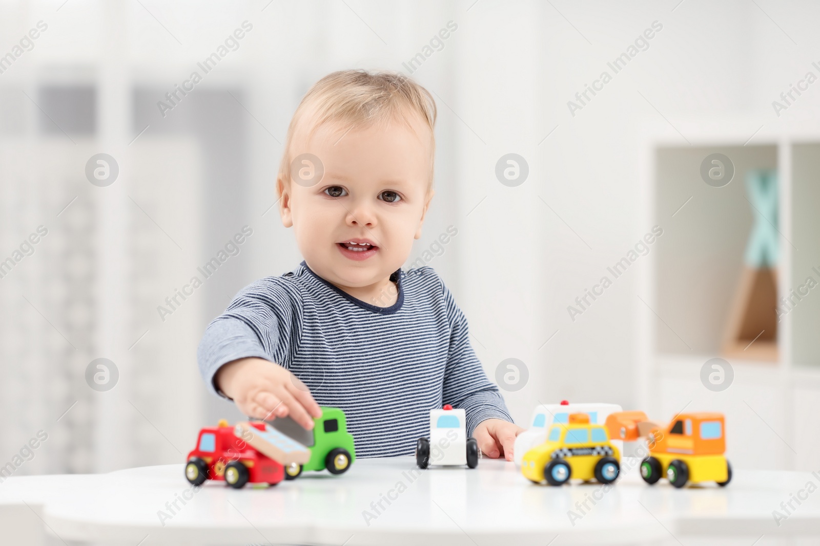 Photo of Children toys. Cute little boy playing with toy cars at white table in room