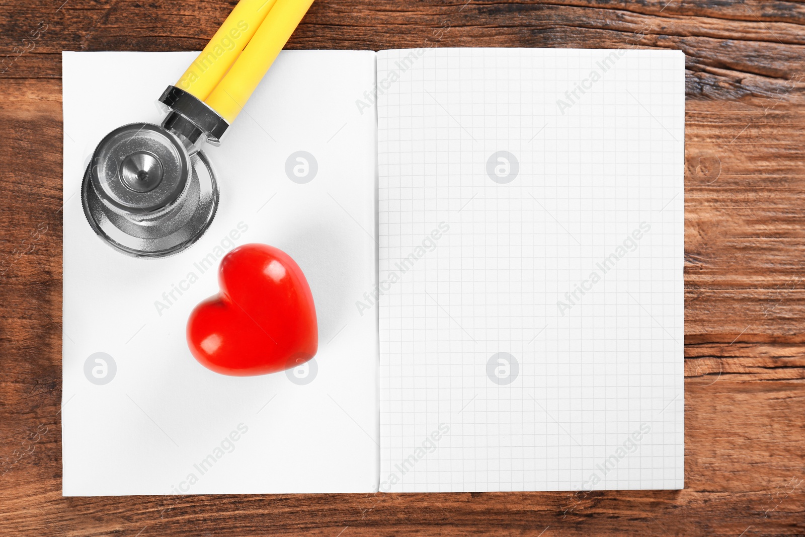 Photo of Stethoscope, open copybook and red heart on wooden background. Heart attack concept