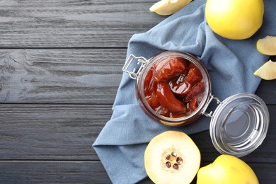 Photo of Quince jam in glass jar and fresh raw fruits on grey wooden table, flat lay. Space for text