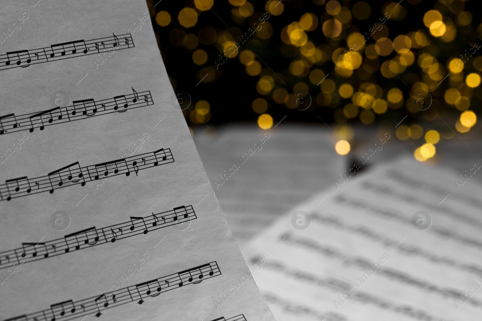 Photo of Closeup view of note sheet against blurred lights. Christmas music