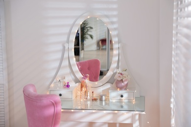 Photo of Elegant dressing table with lights and pink chair in stylish room interior