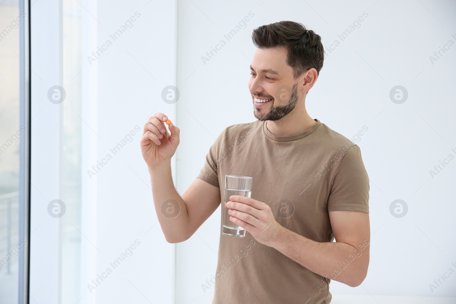 Photo of Young man taking vitamin indoors