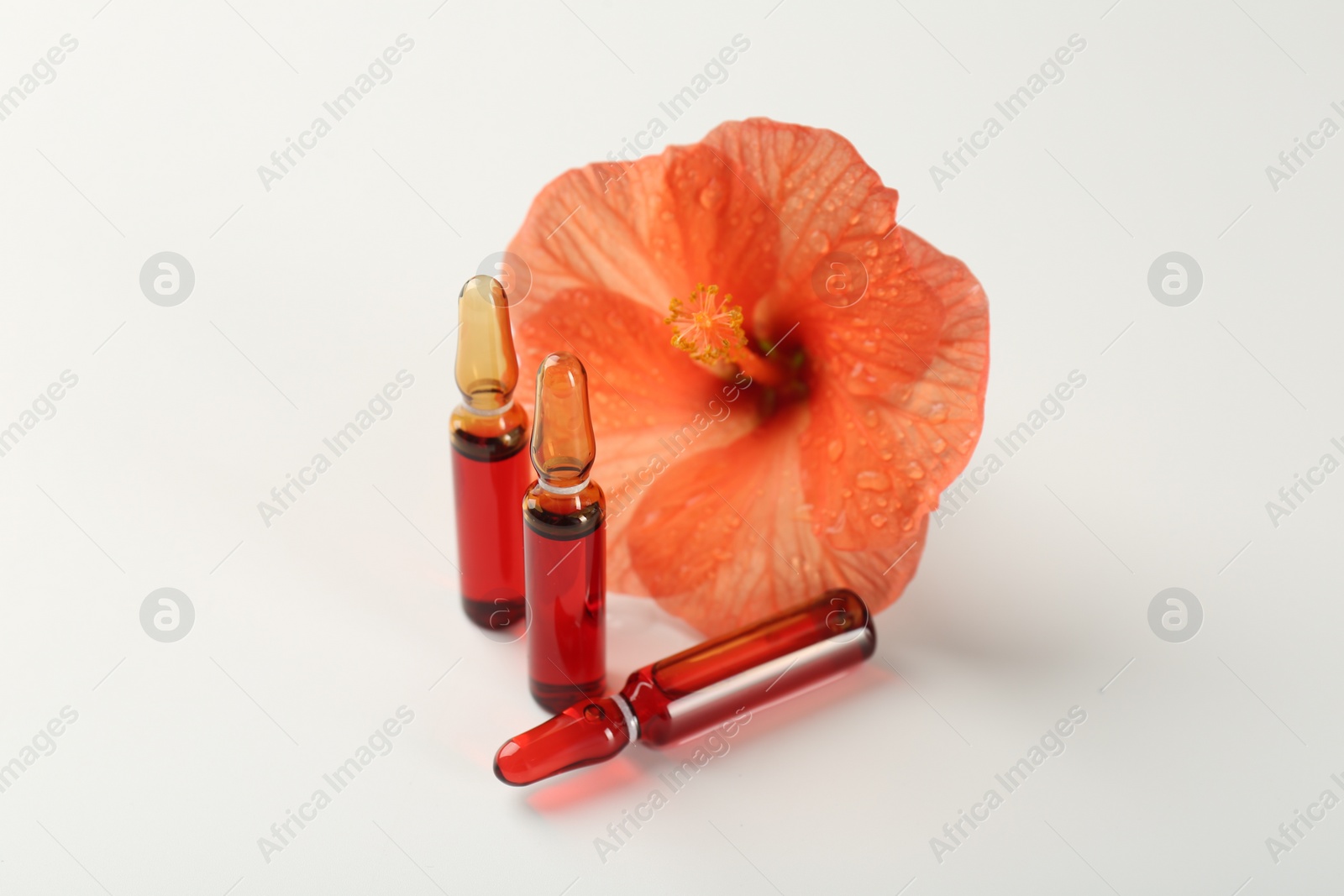 Photo of Skincare ampoules and hibiscus flower on white background