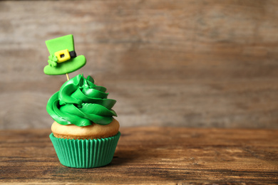 Decorated cupcake on wooden table, space for text. St. Patrick's Day celebration