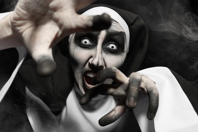 Photo of Scary devilish nun frightening on black background. Halloween party look