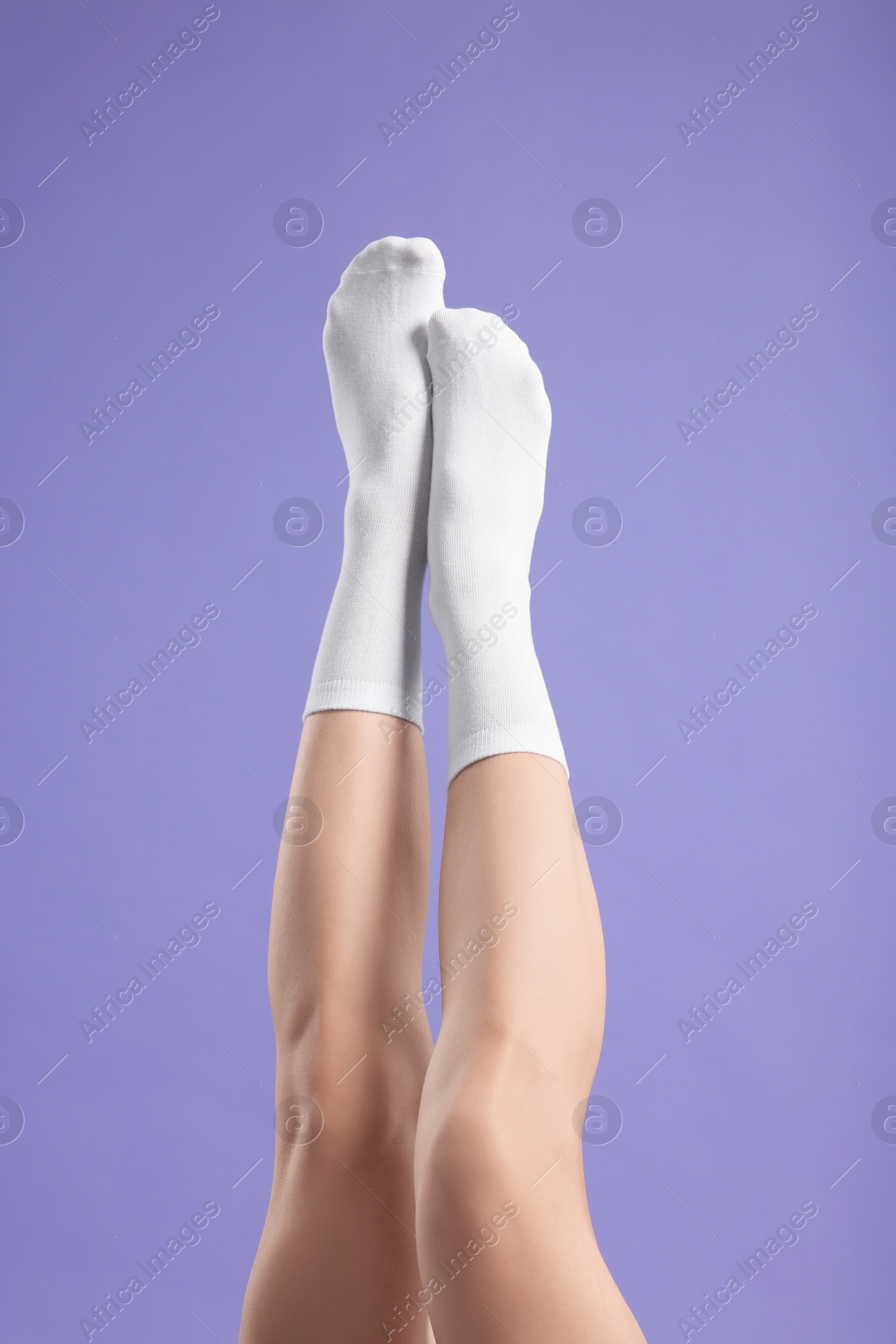 Photo of Woman in stylish white socks on violet background, closeup