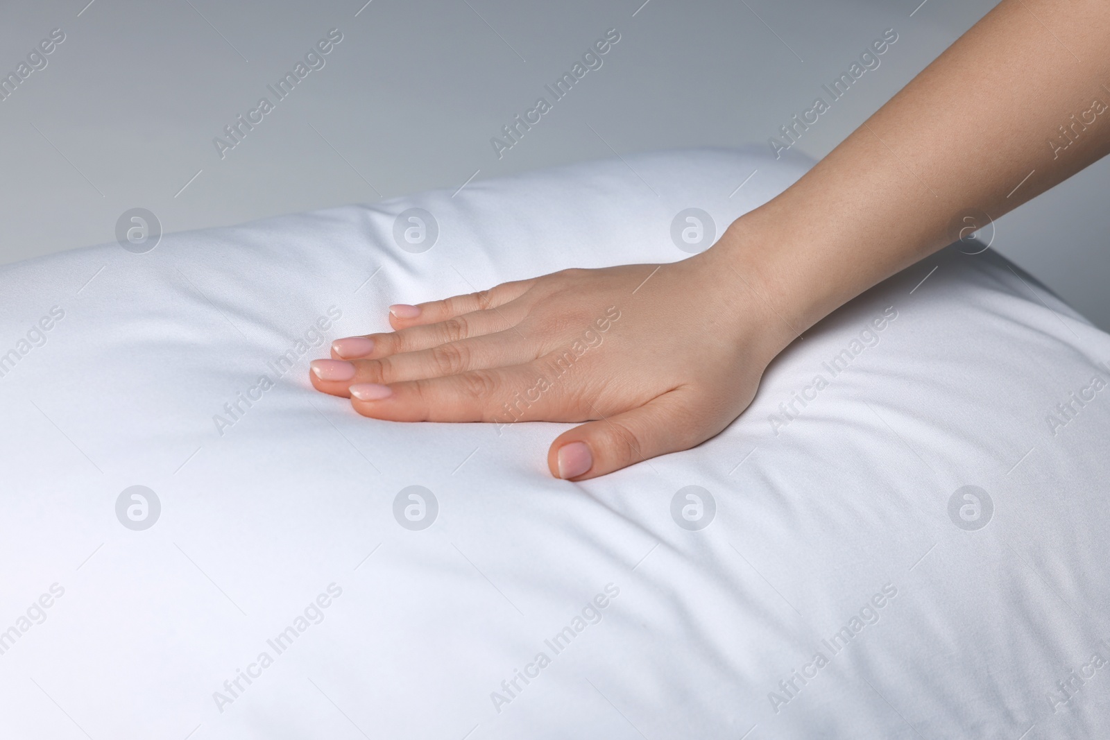 Photo of Woman touching soft white pillow on bed, closeup