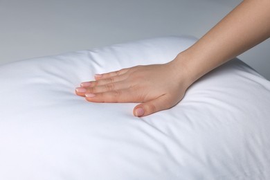 Photo of Woman touching soft white pillow on bed, closeup