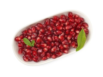 Ripe juicy pomegranate grains and leaves in bowl isolated on white, top view