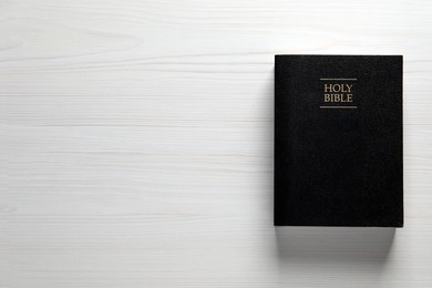 Photo of Holy Bible on white wooden table, top view. Space for text