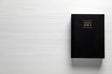 Holy Bible on white wooden table, top view. Space for text