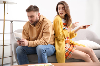 Photo of Couple addicted to smartphones ignoring each other at home. Relationship problems