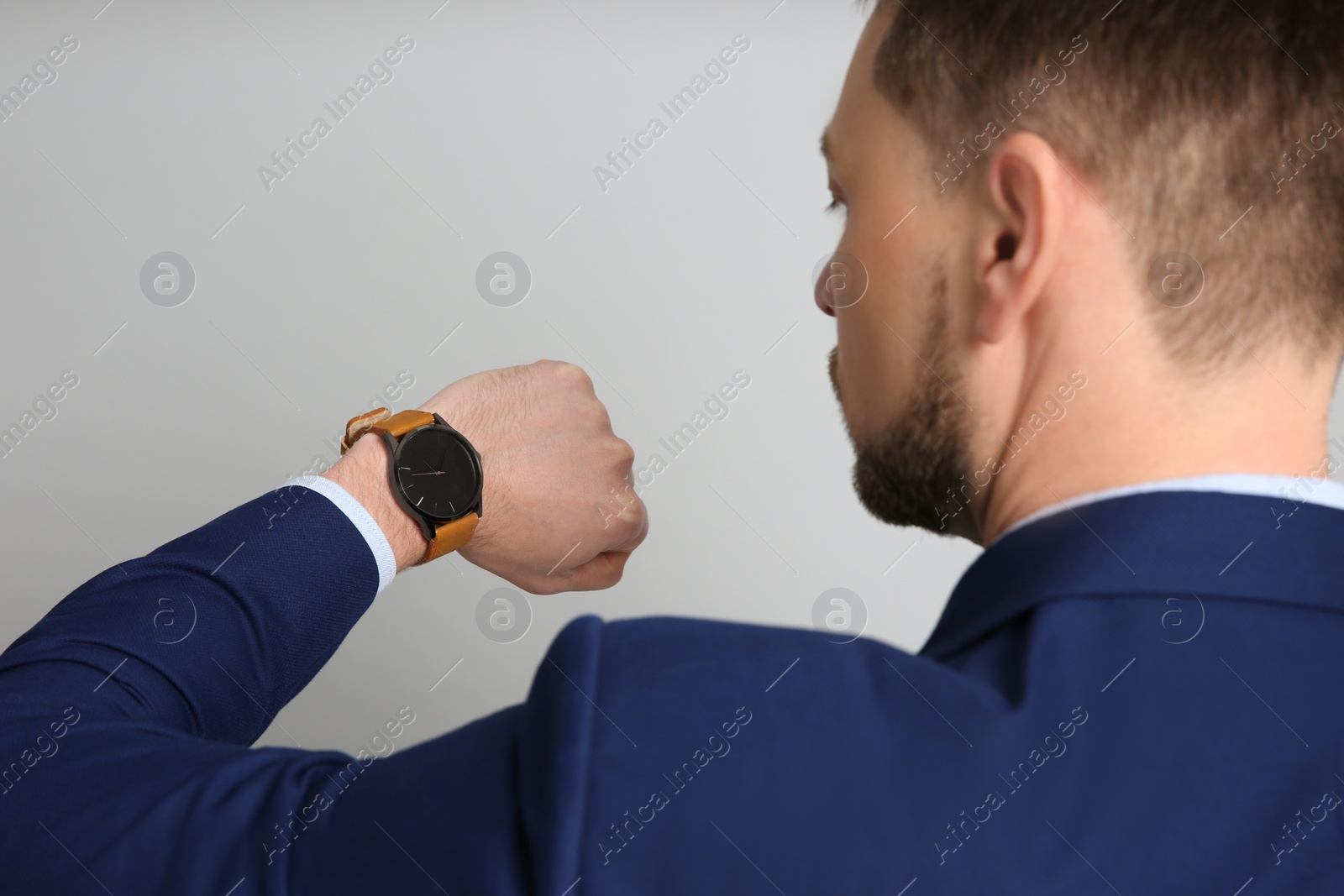 Photo of Businessman looking at wristwatch on grey background. Time management