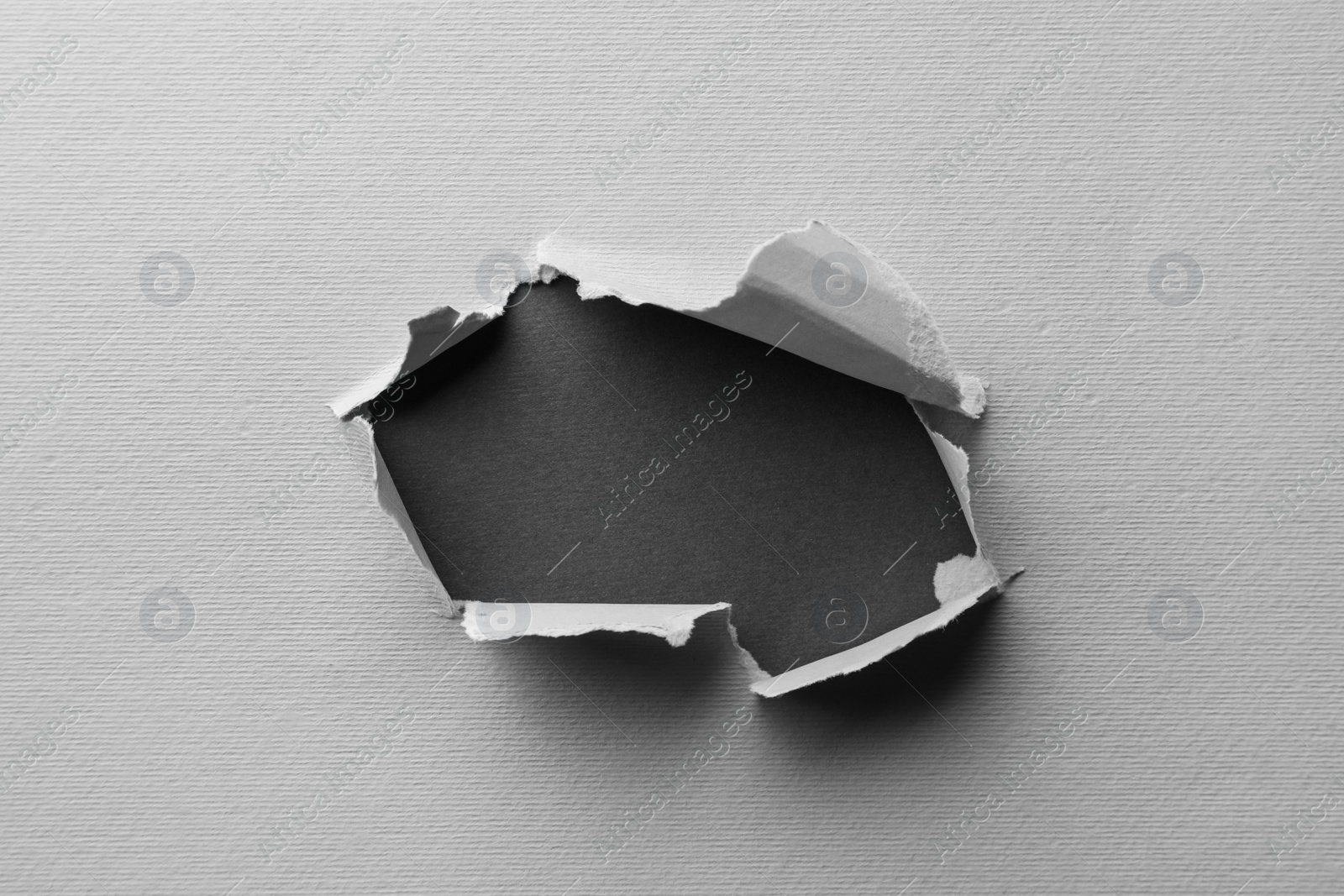 Photo of Hole in white paper on black background