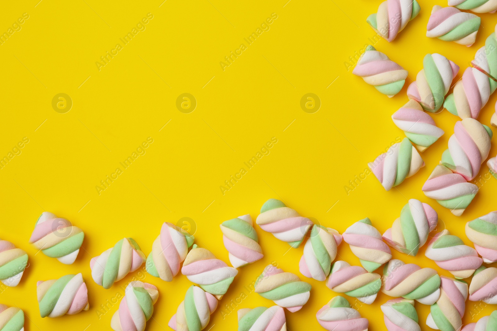 Photo of Delicious colorful marshmallows on yellow background, flat lay. Space for text