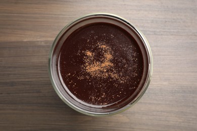 Glass of delicious hot chocolate on wooden table, top view