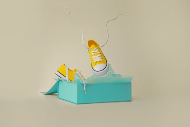 Box with pair of yellow classic old school sneakers on light grey background