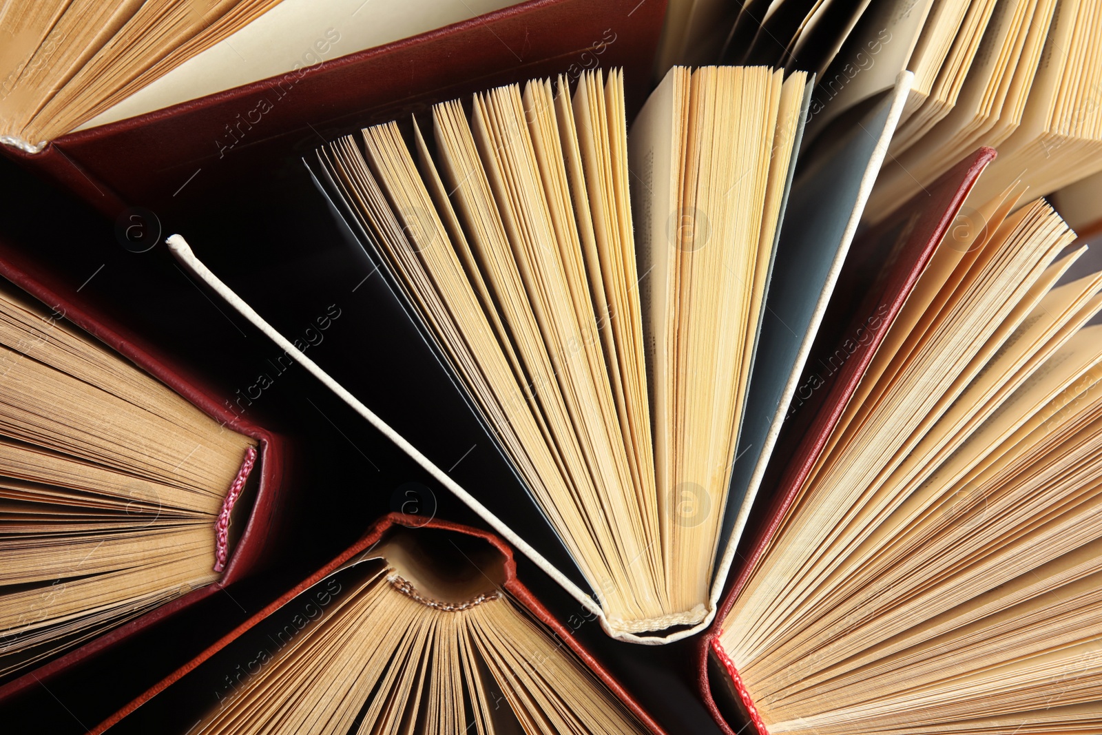 Photo of Many different hardcover books on dark background, top view