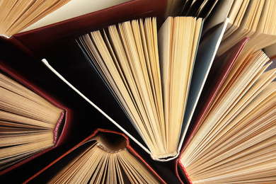 Photo of Many different hardcover books on dark background, top view