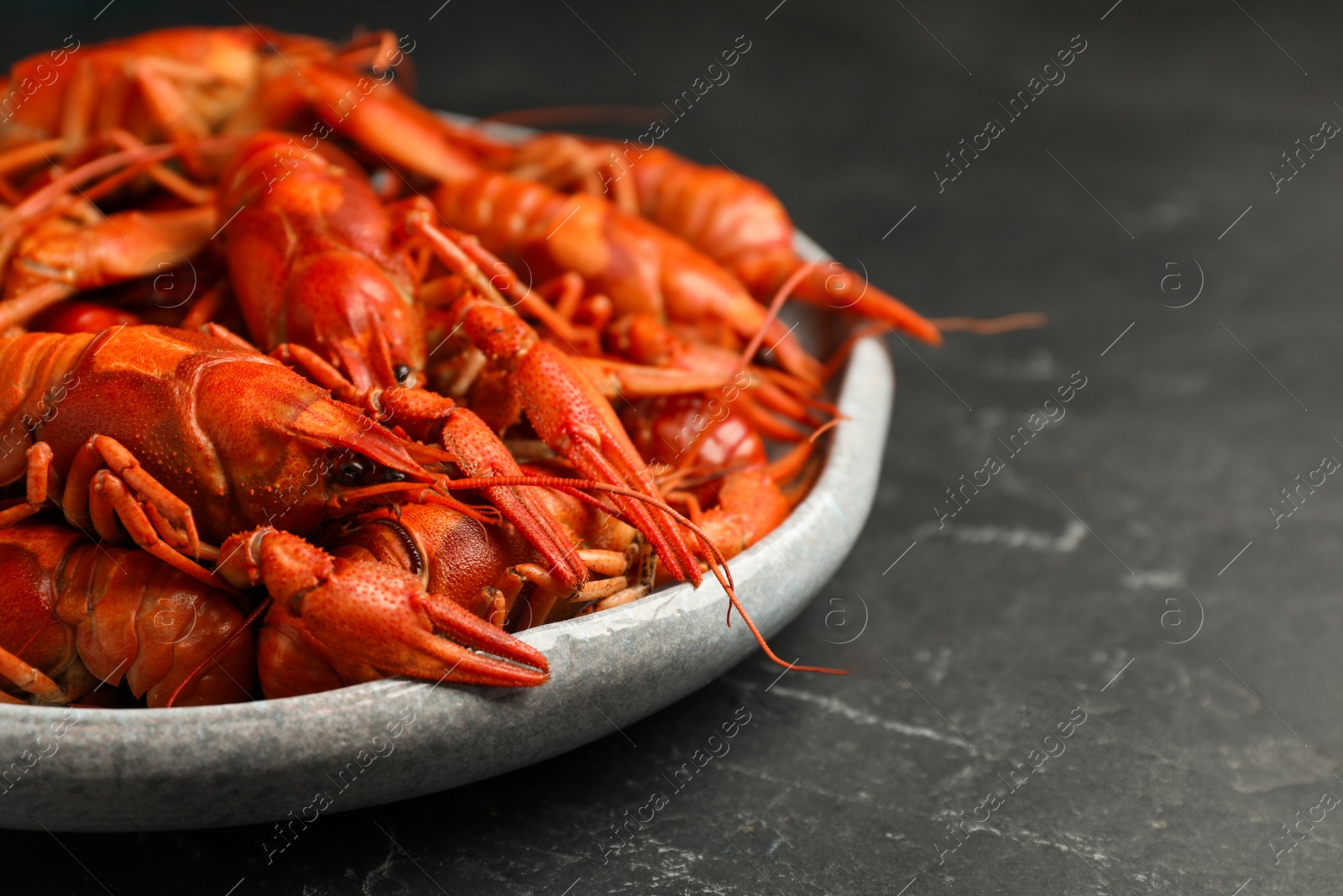 Photo of Delicious boiled crayfishes on black table, closeup